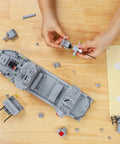 Destroyer Battleship Building Set With 528 Pieces For Kids And Adults Interactive Warship Model With Rotating Main Guns Realistic Deck Details Durable Build Great For STEM Play Imaginative Ocean Warfare Creations, gray model being assembled on table