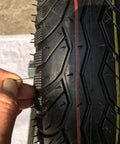 Close-up of a hand inserting a pin into a tread of a six inch pneumatic rubber caster wheel, highlighting its material.