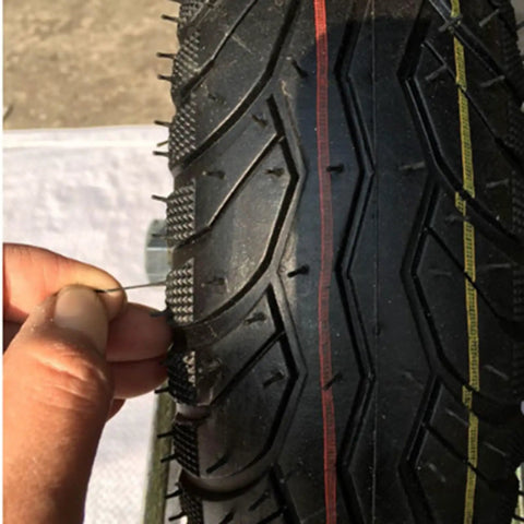 Close-up of a hand inserting a pin into a tread of a six inch pneumatic rubber caster wheel, highlighting its material.