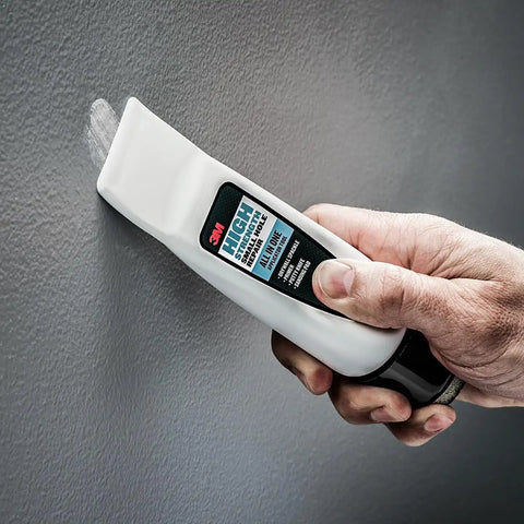 Hand holding All In One Wall Repair Kit With Putty Knife Spackle And Sanding Pad For Quick Fix Of Nail Holes And Small Dings