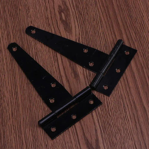 Two black 4-inch T-shaped hinges from the 12 Pack 4 Inch T Shaped Rustproof Iron Light Duty Hinge Set In Black For Sheds Gates And Doors Durable Corrosion Resistant Easy Install With 6 Screw Holes Quiet Smooth Swing Built To Last Ideal For Indoor Outdoor Use resting on a wooden surface.