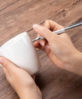 Person using Top Tier Two Pack Tungsten Carbide Scribe Pens to mark on a white mug with a strong grip.