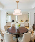 16" White and Gold Drum Pendant Light with Metal Lantern Fabric Shade over a round dining table in a modern kitchen.