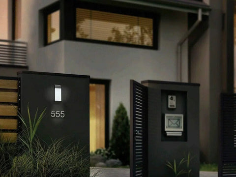 Modern home entrance at night with Solar Powered Post Accent Lights Set Of 4 For Outdoor Use Black Lights With Warm Glow illuminating pathway.