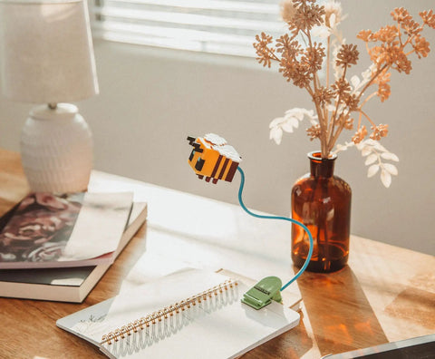 Yellow Bee Totally Battery Powered Reading Light With Clip And Adjustable Arm on desk with notebook and vase