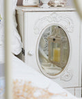 Antique white cabinet with oval mirror featuring Six Pack Resin Beach Conch Cabinet Knobs in a bedroom setting