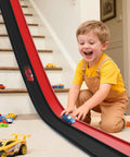 Child playing with Flexible 15 Ft Race Track Starter Set With Strong Suction Cups For Kids 3 Plus Roll Up Track Works On Stairs