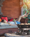 Woman relaxing near a Portable Propane Fire Pit 21 Inch Smokeless Gas Firebowl With 58,000 BTU No Mess Campfire on patio