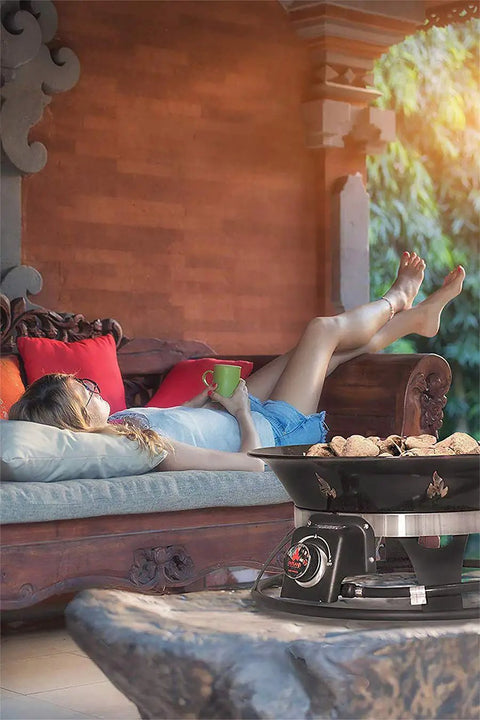 Woman relaxing near a Portable Propane Fire Pit 21 Inch Smokeless Gas Firebowl With 58,000 BTU No Mess Campfire on patio