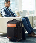 Businessman with laptop beside Softside Expandable Carry On Luggage 22 Inch By 14 Inch By 9 Inch Airline Approved 20 Inch Wheeled Suitcase