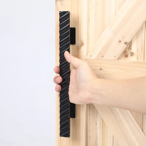 Hand holding solid brass sliding barn door handles set featuring 12 inch two sided design heavy duty mounting hardware installed