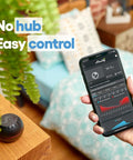 Person holding a smartphone with app displaying 24.3°C readings next to HT Black WiFi Temperature And Humidity Sensor, smart home setup.