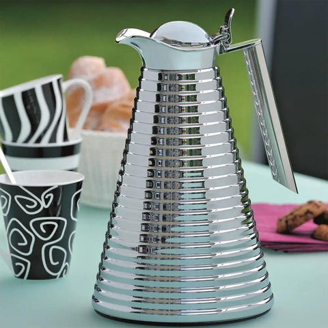 Glass Vacuum Copper Carafe With Chrome Plated Spout And Stainless Steel Handle Keeps Hot For 12 Hours And Cold For 24, 1.0 L Capacity, Dope Chrome Finish, Insulated Beverage Server For Hot And Cold Drinks on a table with cups in the background.