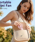 Woman placing pink fan from Four Pack USB Rechargeable Mini Handheld Fans Set with 3 speeds into a beige handbag