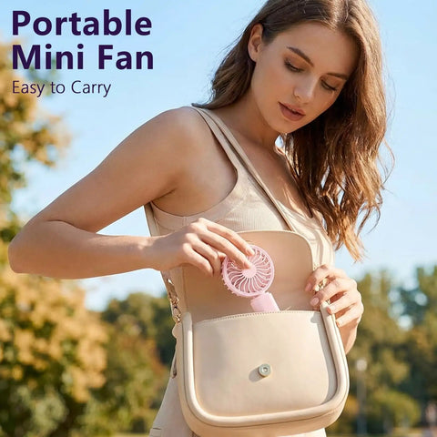 Woman placing pink fan from Four Pack USB Rechargeable Mini Handheld Fans Set with 3 speeds into a beige handbag
