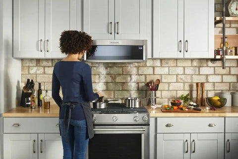 Woman cooking under a range hood equipped with Genuine OEM Hood Charcoal Filters For Ranges 3 Pack Replacement For 1938124 AH3494894