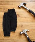 Black Waterproof Arm Sleeves Two Pack Heavy Duty Grease Shield For Mechanics And Construction Crews Slick Proof Work Cover With Snug Stretchy Fit Easy Rinse Job Ready Protection on wooden surface with hammer.