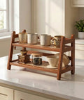 Two Tier Bamboo Coffee Station Organizer For Mugs And Cups, Space Saving Countertop Rack For Kitchen And Coffee Bar, Matcha Stand, Dark Gray Finish, Durable Bamboo Mug Holder To Tidy Your Home Cafe Setup with various mugs and accessories on a white kitchen countertop.