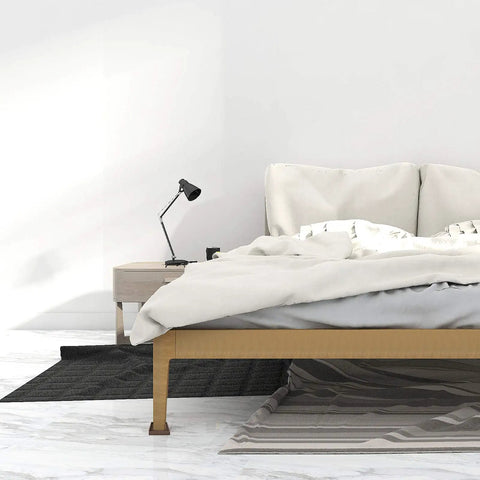 Minimalist bedroom with a wooden bed, bedside lamp, and decorative rugs on hardwood floor.