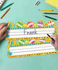 Child writing on 50 Pack Hot Air Balloon Style Desk Nameplates For Students, colorful name tags with balloon decor, 3.4x9.5 inches.