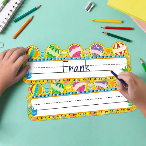 Child writing on 50 Pack Hot Air Balloon Style Desk Nameplates For Students, colorful name tags with balloon decor, 3.4x9.5 inches.