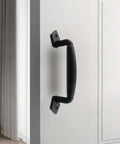 Black steel 8 inch sliding barn door handle installed on white cabinet door, showing sturdy construction and modern farmhouse design.