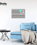 Custom Printed Canvas Bulletin Board With Graphite Grey Bold Stripe Design, 30 By 20 Inches, Framed In Satin White Frame, Ready To Pin Photos, Notes, And Recipes installed on a wall above a blue sofa.