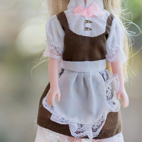Doll wearing a brown dress with lace, featuring golden metal buttons for 100Pc Mini Buttons For Doll Clothes DIY Fasteners Kit.
