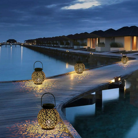 Outdoor Solar Lanterns Hanging Lights For Patio Porch Backyard Decorative Garden Lamps Metal Waterproof LED Lanterns With Auto On Off No Fuss Easy Setup Create Charming Shadow Patterns Two Pack illuminating a wooden boardwalk at night.