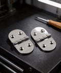 Two Pack Heavy Duty Oval Hinges in 316 Stainless Steel for Outdoor Cabinets, Boat And RV Doors, Marine Grade, Corrosion Resistant, Smooth Quiet Operation, Built Tough For Harsh Environments. Two oval 316 stainless steel hinges on a dark work surface
