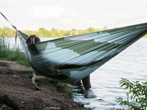 Person relaxing in Roo Double Hammock with GravitasX water resistant breathable ripstop fabric by the lake