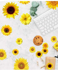 72 Pieces Sunflower Wall Sticker Set Peel And Stick 3D Removable Waterproof Decals scattered on marble surface with keyboard and gifts