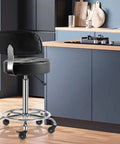 Lockable Boss Ergonomic Rolling Stool With Backrest And Foot Rest, hydraulic height adjustable, in kitchen setting, black