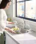 Woman using One-Handle Pullout Kitchen Faucet With Power Clean Spray Tech, Modern Chrome Finish, washing grapes in sink