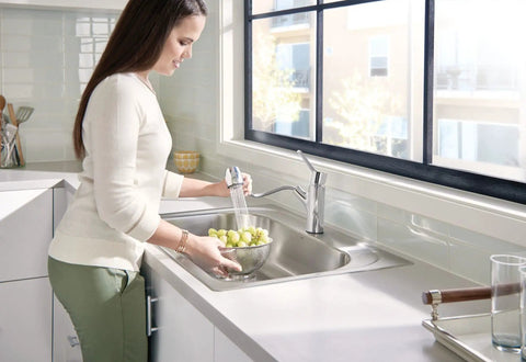 Woman using One-Handle Pullout Kitchen Faucet With Power Clean Spray Tech, Modern Chrome Finish, washing grapes in sink
