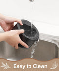Person washing durable granite mortar and pestle set with wood base for grindin herbs and spices in kitchen sink.