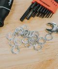Close-up of aluminum round spacers/washers scattered on a workbench; unthreaded, silver metal for bolts.