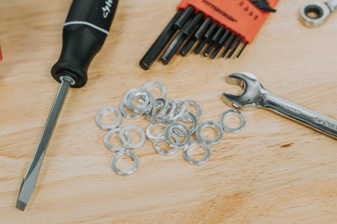 Close-up of aluminum round spacers/washers scattered on a workbench; unthreaded, silver metal for bolts.