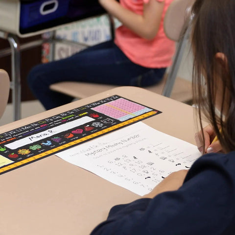 Top Shelf Chalkboard Style K-2 Desk Reference Mats on a desk with a student completing a worksheet, premium plastic teaching aids.