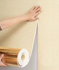 Person applying 6mm Thick Peel And Stick Foam Wall Panel Rolls with aluminum foil backing to textured wall.