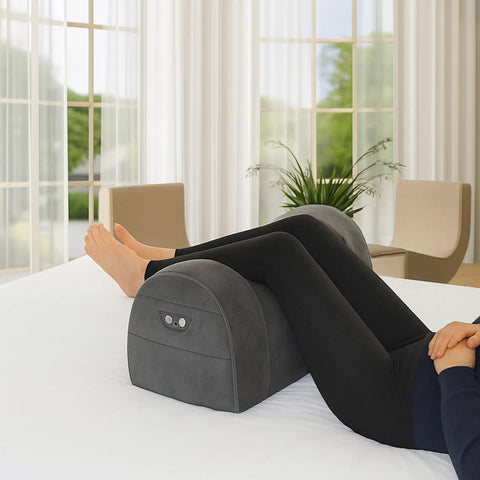 Carepeutic Contoured Leg Rest Wedge With Vibration Massage And Heat placed on a bed supporting legs, featuring a grey soft touch surface.