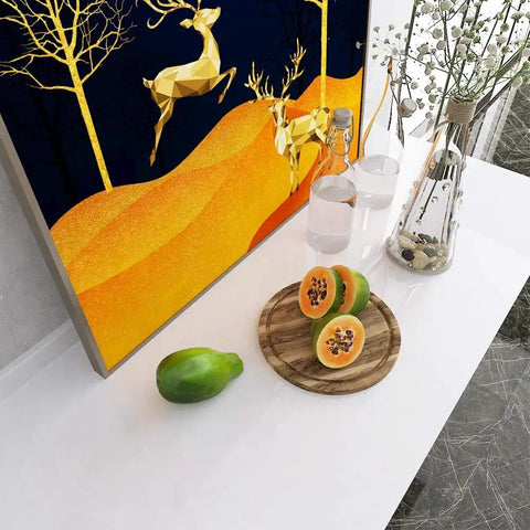 Still life with papaya, glass bottles, and decorative wall art on white countertop