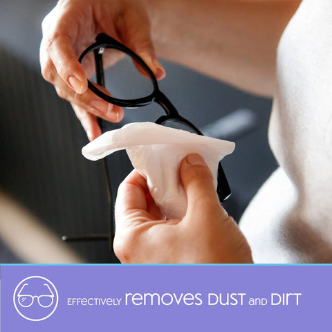 Lens cleaning wipe being used to clean eyeglasses; white disposable wipe held by hands.