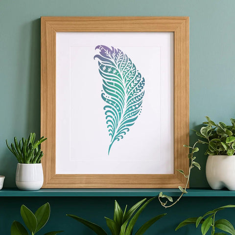 Awesome Boho Feather And Mandala Stencil Set, floral feather art print in a wooden frame against a green wall.
