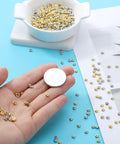 Hand holding 2000 Pcs Gold And Silver Spacer Beads 4Mm Flat Round Disc Beads for DIY Jewelry with a coin for scale