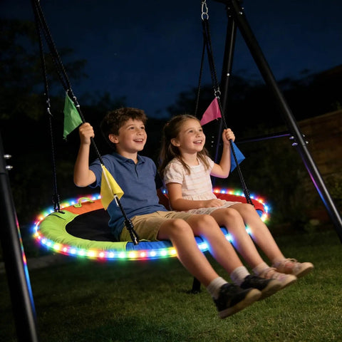 Kids enjoying 40 Inch Flying Saucer Swing With LED Lights And 440 Lbs Capacity, Heavy Duty A-Frame Metal Swing Stand at night