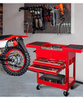 Rolling Garage Toolbox With Directional Wheels Two Drawer Chest Tray Top Work Surface And Storage Push Cart For Shop Or Home Garage Perfect Gift For DIYers And Handy Pros in red next to motorcycle in garage