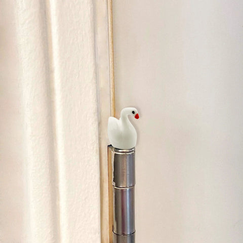 Whimsical Mini Swan Hinge Head Magnets Set Of 6 For Door Decor And Metal Surfaces installed on a door hinge pin.
