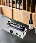 Plug And Play Electric Pvc Bottle Cap Heat Shrinker 110V Tabletop Sealer on countertop with two wine bottles.