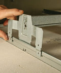 Heavy Duty Grid Brace Ceiling Box Kit With Four Inch Round Box And Two And One Eighth Inch Depth, Concentric Knockouts In One Half Inch And Three Quarter Inch, Sliding Bracket Mount, Mount Anywhere On The Bracket For Twenty Four Inch Spans, showing hand adjusting mount on ceiling grid.